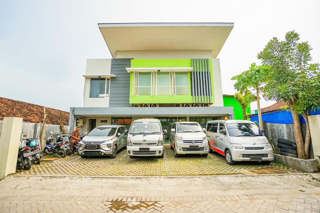 un gruppo di auto parcheggiate di fronte a un edificio di Ardhya Guesthouse Syariah by ecommerceloka a Sidoarjo