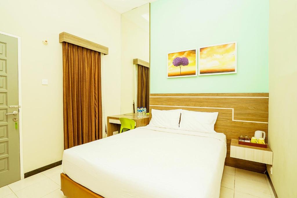 una camera da letto con un grande letto bianco in una stanza di Ardhya Guesthouse Syariah by ecommerceloka a Sidoarjo