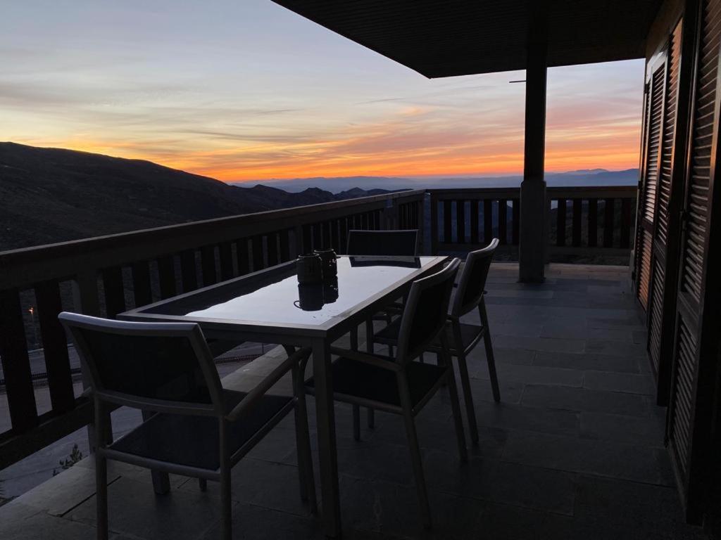 un tavolo e sedie su un balcone con vista sul tramonto di Ático con vistas increibles a pie de pista y garaje incluido a Sierra Nevada
