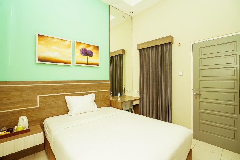 una camera da letto con un letto bianco in una stanza di Ardhya Guesthouse Syariah by ecommerceloka a Sidoarjo