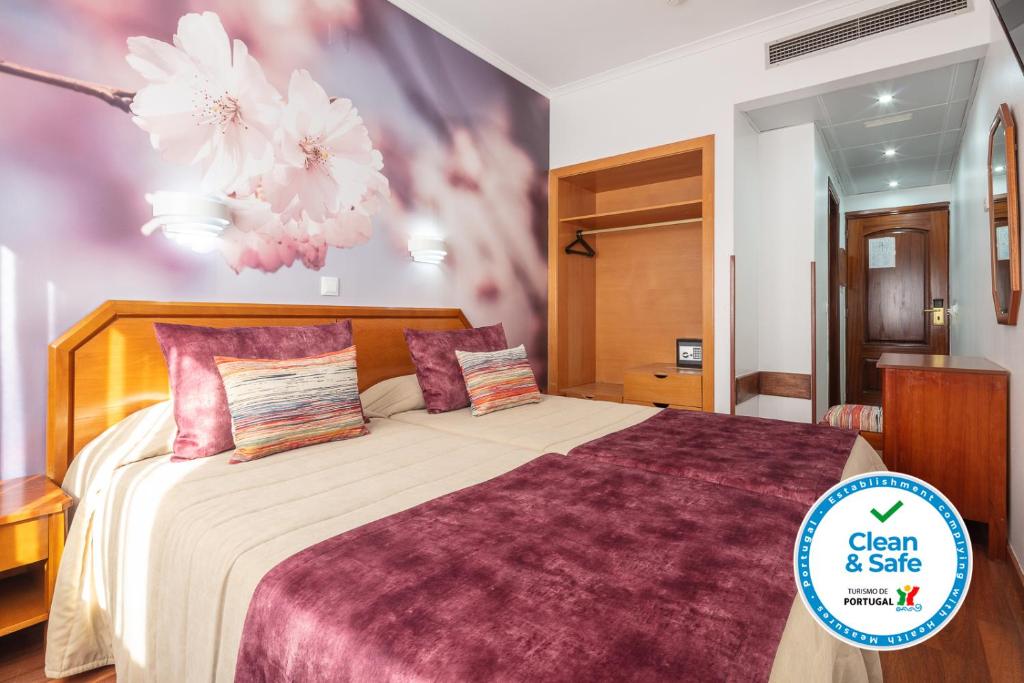 a bedroom with a large bed with flowers on the wall at Hotel Anjos in Lisbon