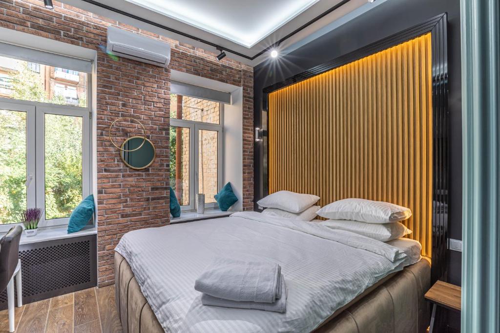 Un dormitorio con una cama grande y una pared de ladrillo. en Luxury Urban Lofts Across Baseina 5а & Arena, en Kiev