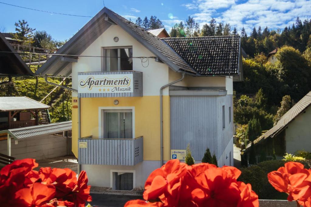 a small building with red flowers in front of it at Apartment Muznik in Bled