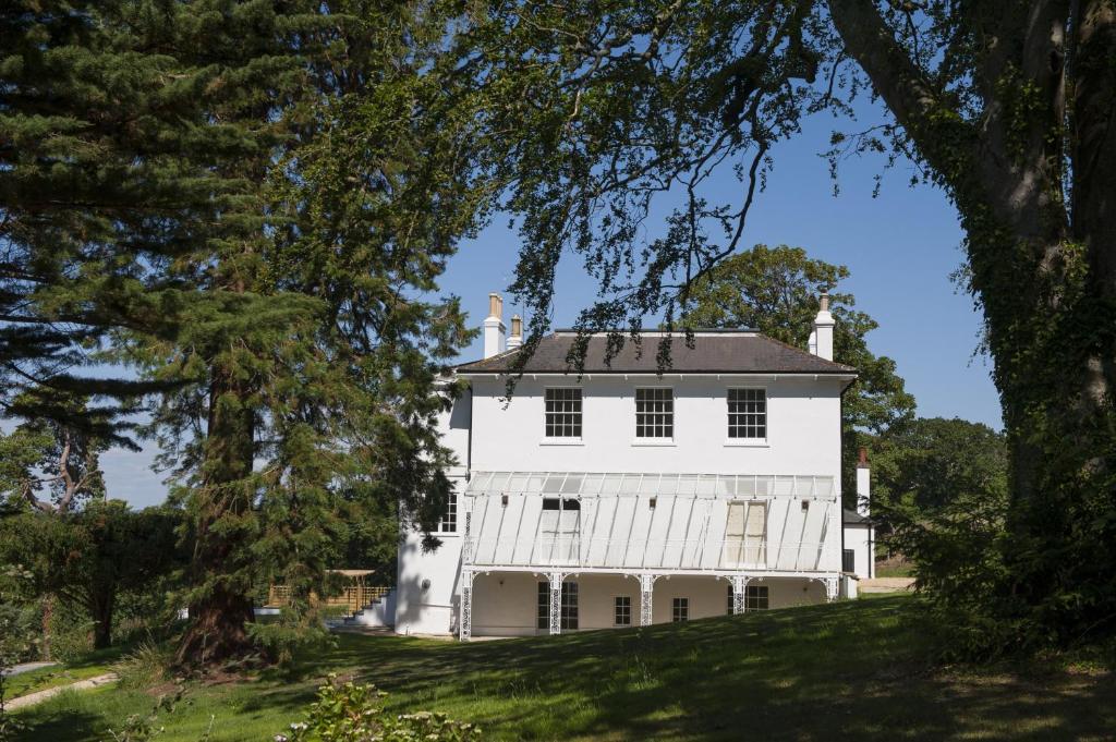 ein weißes Haus auf einem Hügel mit Bäumen in der Unterkunft The Garden Flat in Charmouth