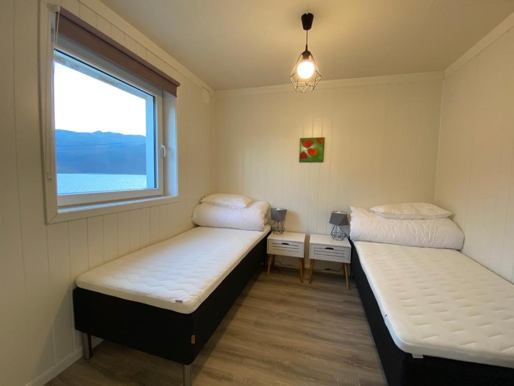 two beds in a small room with a window at Waterfront Senja 2 in Torsken