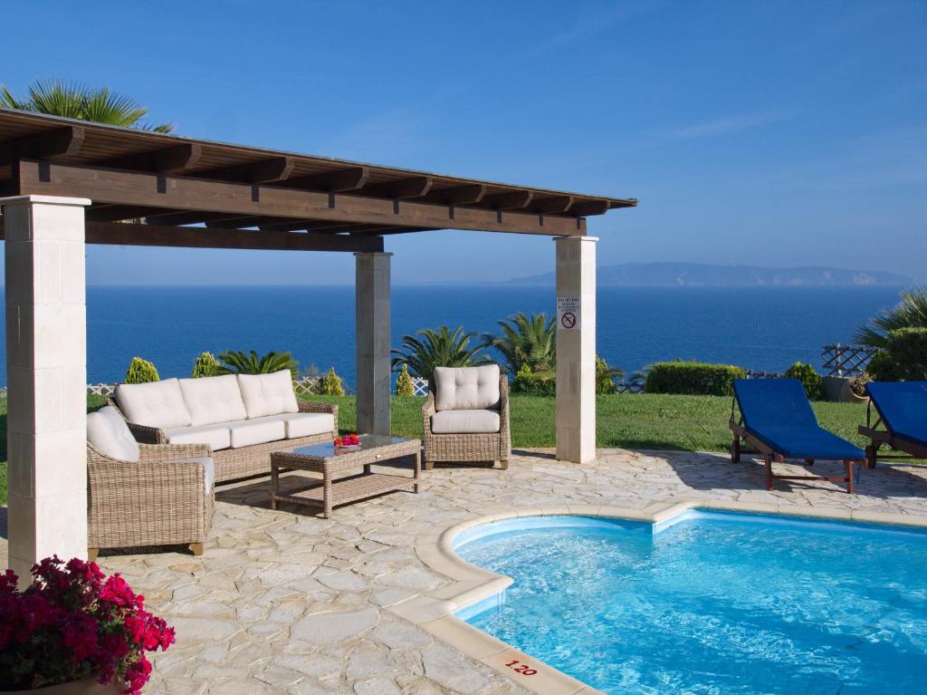 a patio with a pool and chairs and a pergola at Villa Dimitra in Trapezaki
