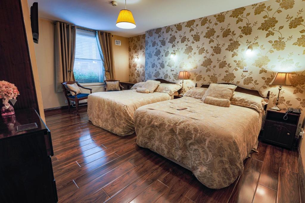 Cawley's Guesthouse في Tobercurry: غرفة فندقية بسريرين وكرسي