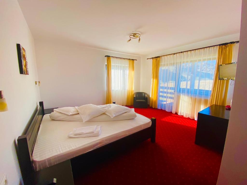 a bedroom with a bed with a red carpet at Pensiunea Soarelui in Fundata