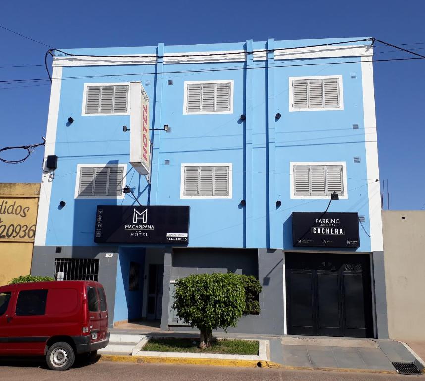 un edificio azul con una furgoneta roja aparcada delante en Macaripana en Gualeguaychú