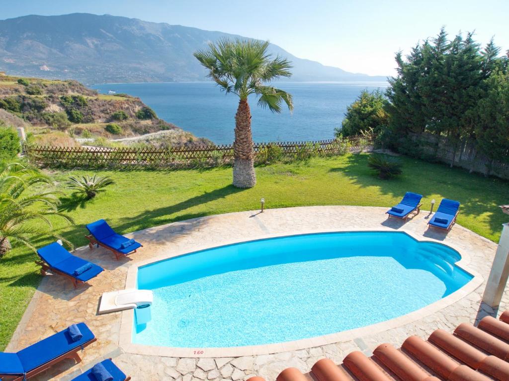 una piscina con sillas, una palmera y el océano en Villa Eros Spartia Kefalonia en Spartia