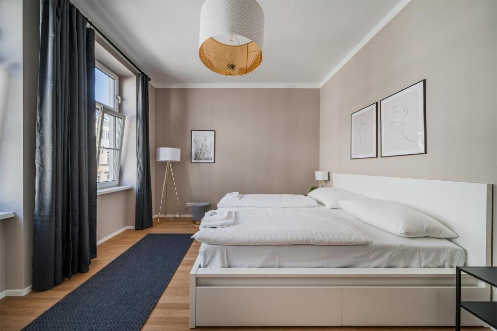 a white bedroom with a bed and a large window at easy flat Margareten Apartments in Vienna