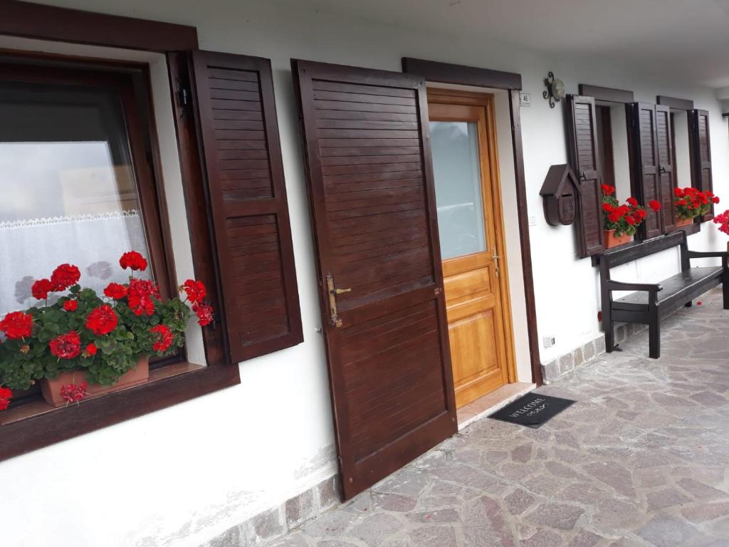 ein Paar Türen mit roten Blumen auf einem Gebäude in der Unterkunft Appartamento In Montagna in Venas