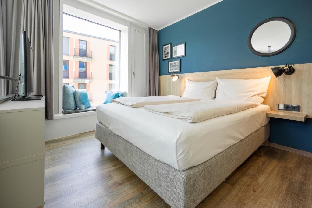 a bedroom with a large bed with a blue wall at HARBR. hotel Konstanz in Konstanz