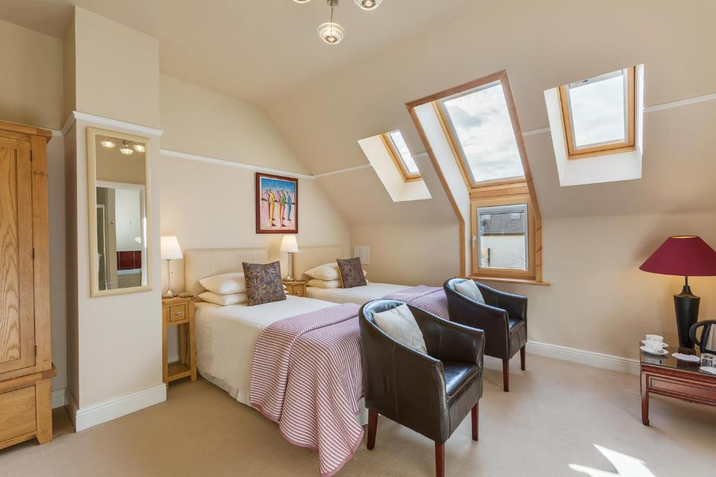 a bedroom with two beds and a desk and chairs at Dún Ard in Dungarvan