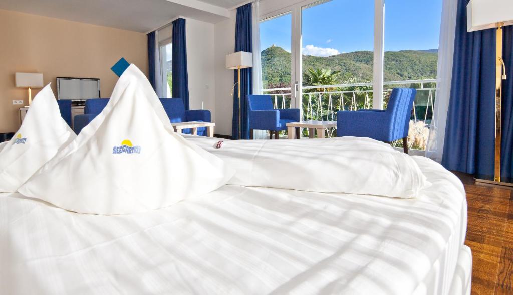 um quarto de hotel com uma cama branca com cadeiras azuis em Seegarten em Caldaro