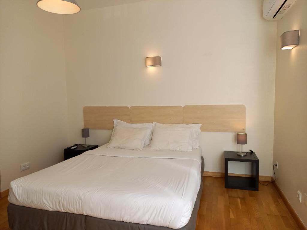 a bedroom with a bed with white sheets and two lamps at Fado Bed & Breakfast - Santos in Lisbon