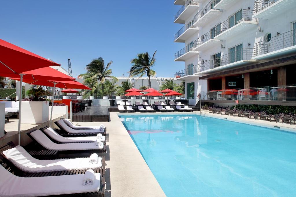 a swimming pool with chairs and umbrellas next to a building at Emporio Veracruz in Veracruz