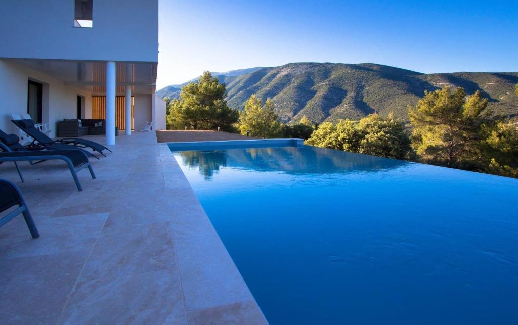 a large blue swimming pool with mountains in the background at À mont nos hôtes in Mollans-sur-Ouvèze