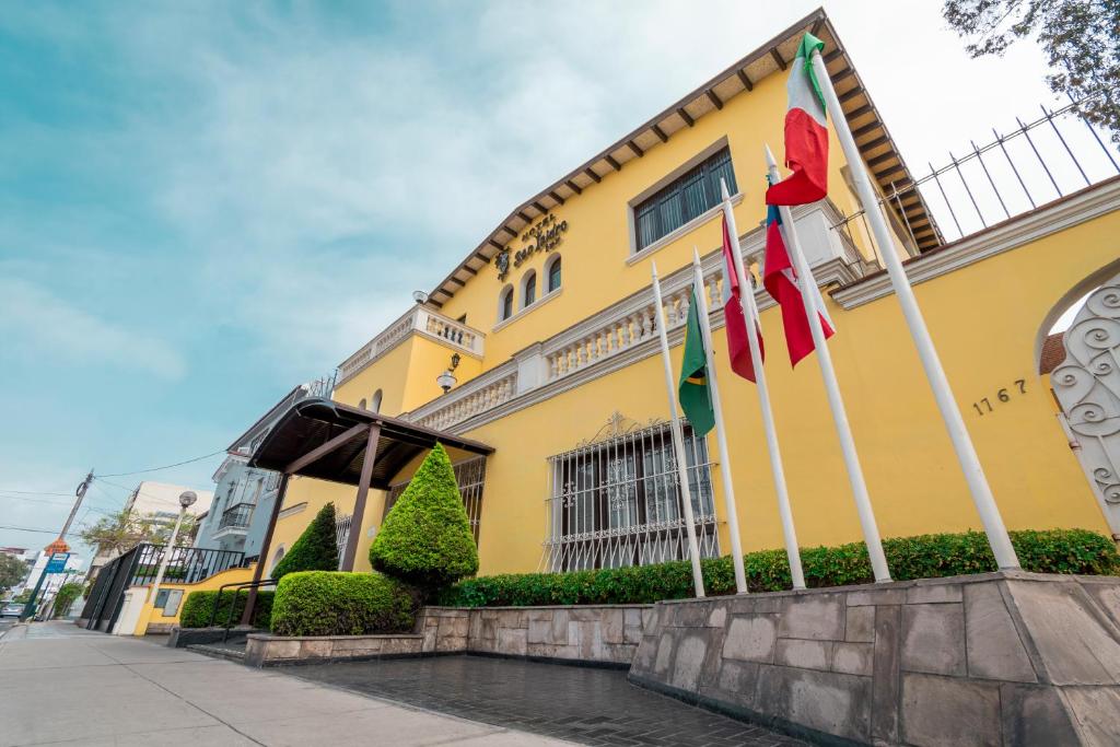 un edificio giallo con bandiere davanti di Hotel San Isidro Inn a Lima