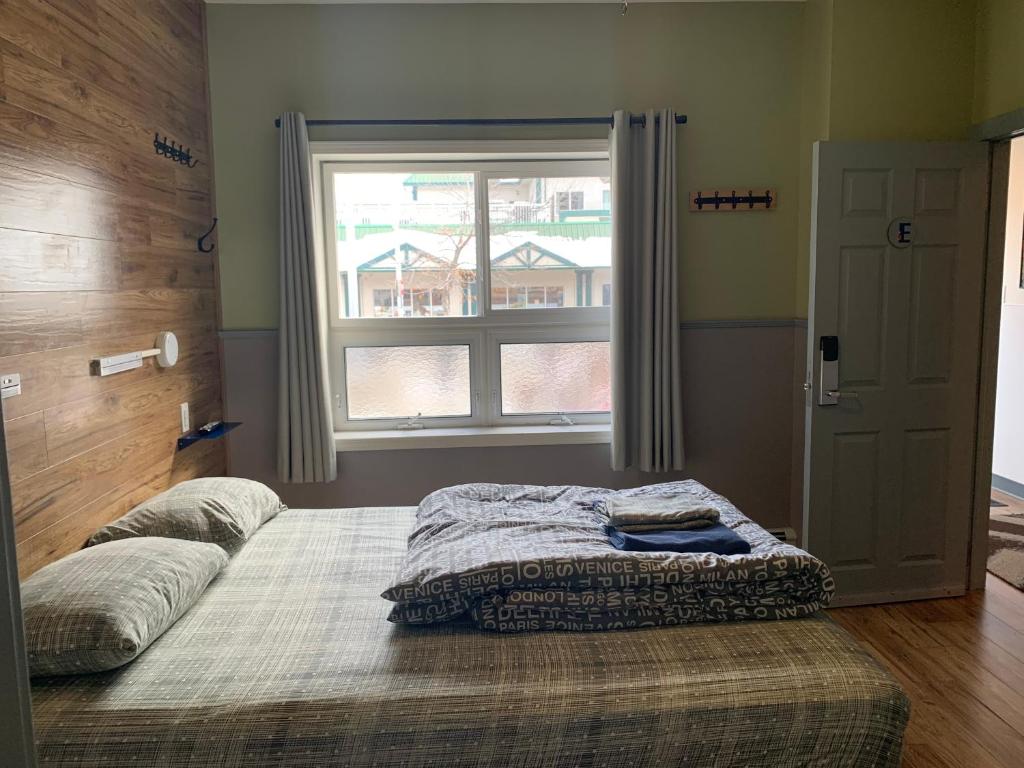 a bedroom with a large bed with a window at Jasper Downtown Hostel in Jasper