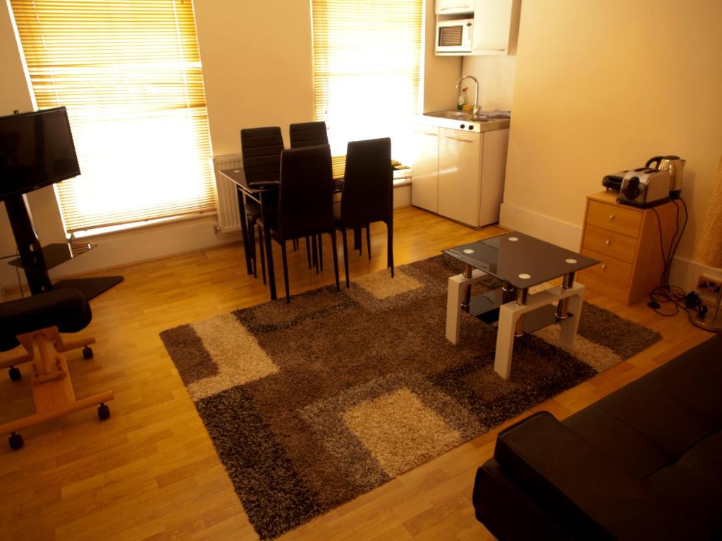 a living room with a table and chairs and a kitchen at Mayfair Flat in London