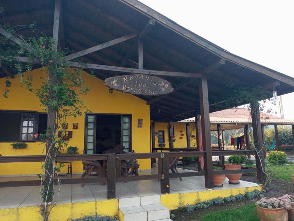a yellow building with a wooden roof and a patio at Casa de campo Recanto das Borboletas in Bom Retiro