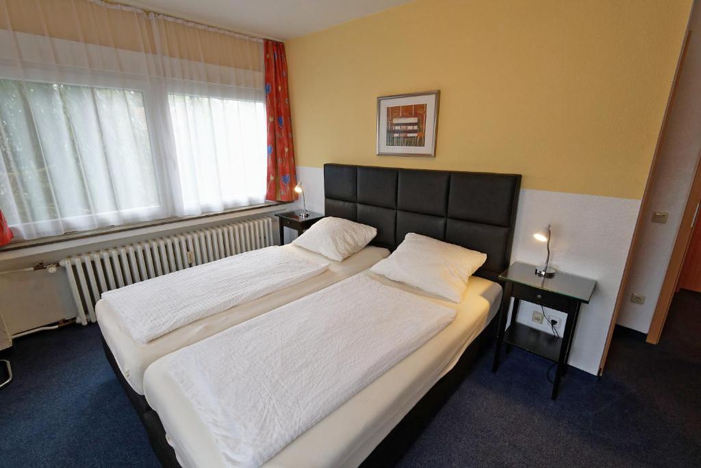 1 dormitorio con 2 camas y ventana en Hotel Wiedenhof, en Hilden