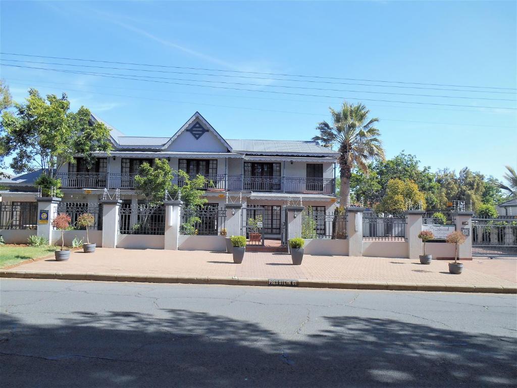 Bloemfontein的住宿－Oakwood Lodge，一座大型白色房子,前面有棕榈树