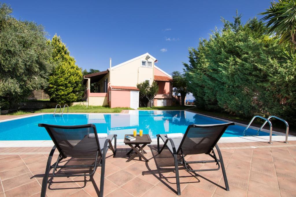 a patio with two chairs and a table next to a pool at Sea View Estate Helios in Perama