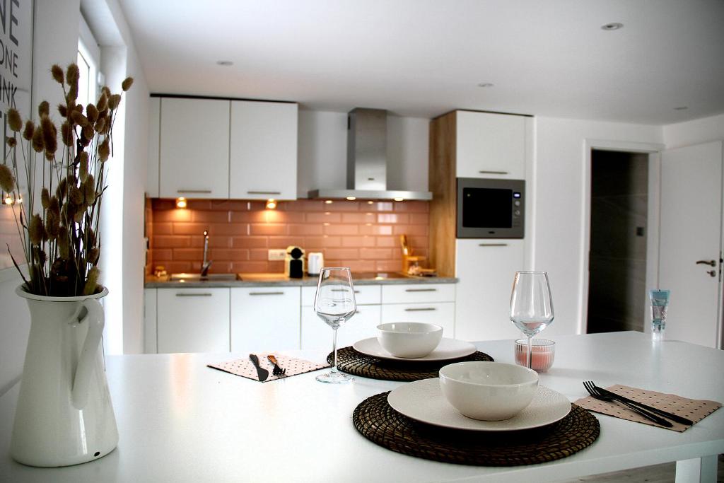 a kitchen with a table with two plates and wine glasses at Appartement Blanc cocooning in Sprimont
