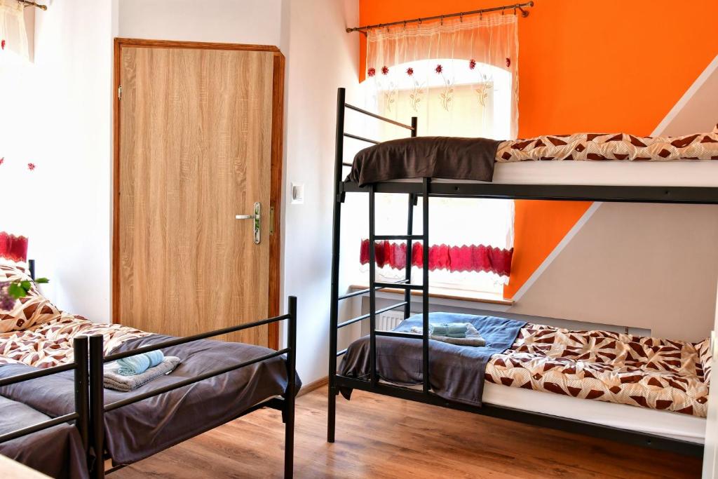 Zielony Dom na Wzgórzu في بستشستا كوودزكا: سريرين بطابقين في غرفة مع جدار برتقالي