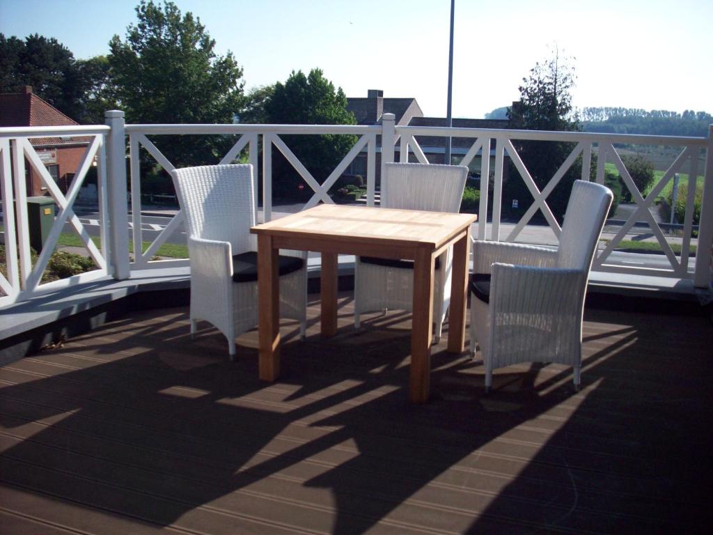 einen Holztisch und vier Stühle auf einer Terrasse in der Unterkunft B&B Wijnendalvallei in Torhout