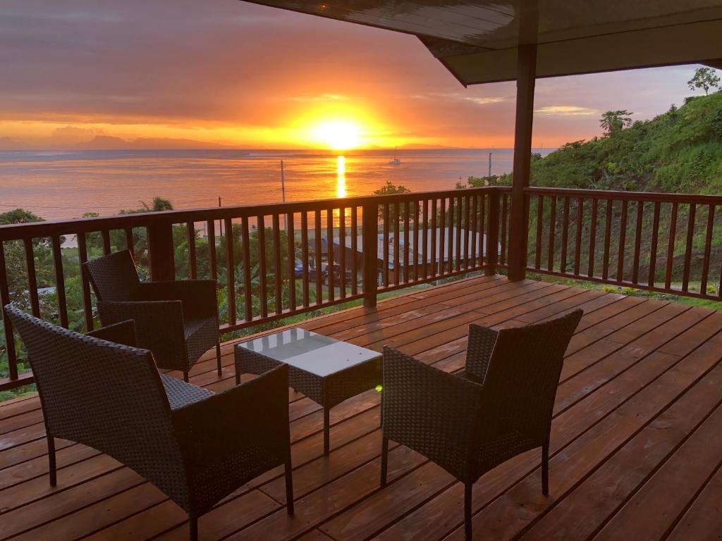Fitii的住宿－Bienvenue au Mati House，一个带椅子和桌子的甲板,享有日落美景