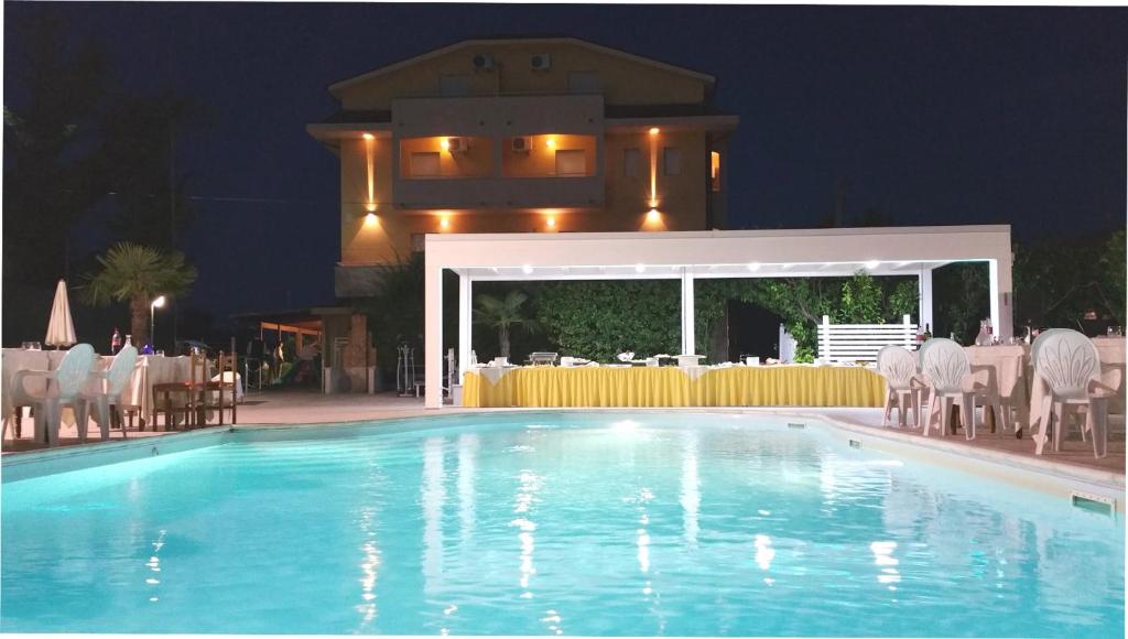 a swimming pool in front of a restaurant at night at Hotel Maria in Pineto