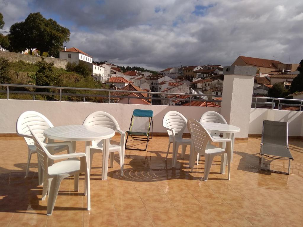 un gruppo di tavoli e sedie bianchi su un tetto di O Terraço da Ribeira a Sertã