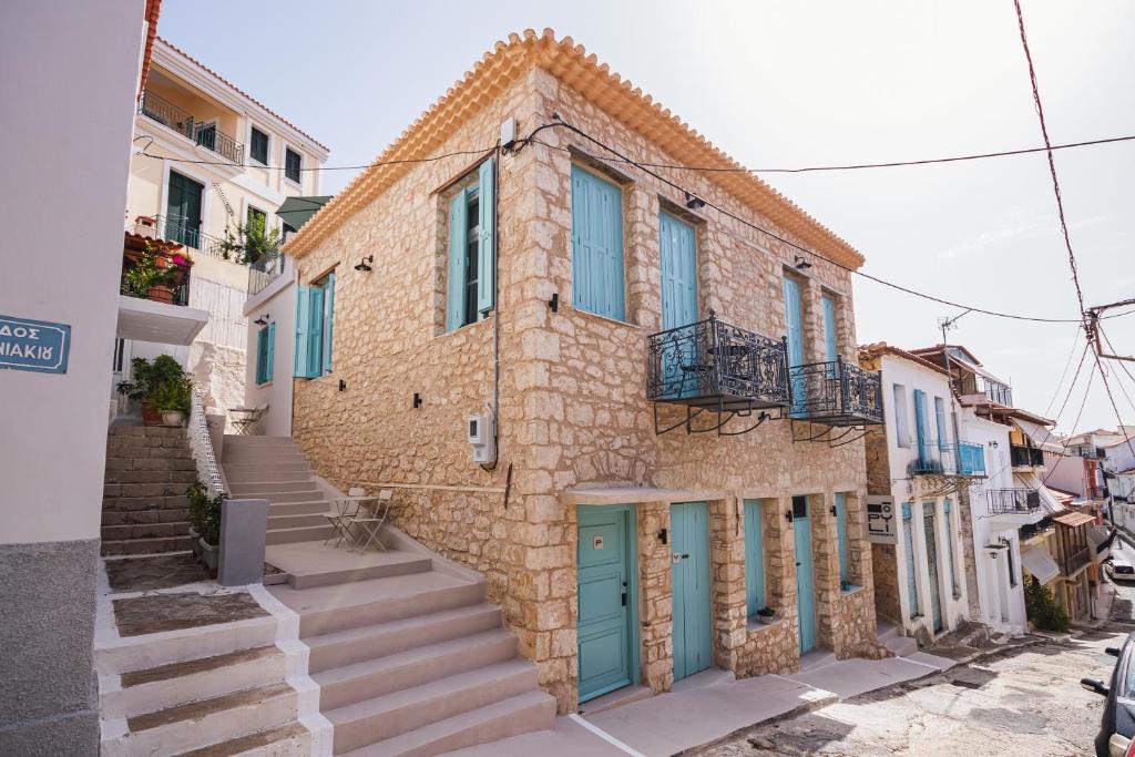 Casa de piedra con puertas y escaleras azules en Pyli Apartments, en Pylos