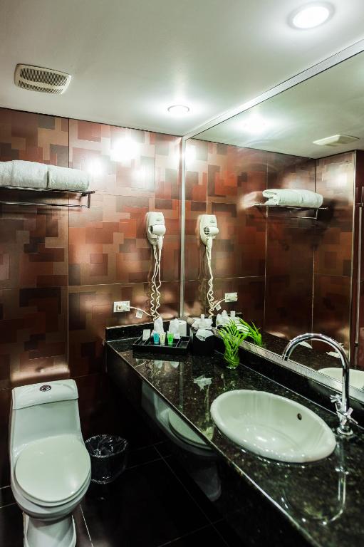 a bathroom with a sink and a toilet and a mirror at Riande Aeropuerto Hotel Casino in Tocumen