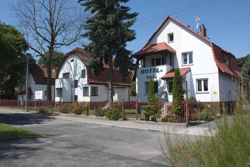 a white house with a fence in front of it at Hotelik Villa in Legnica