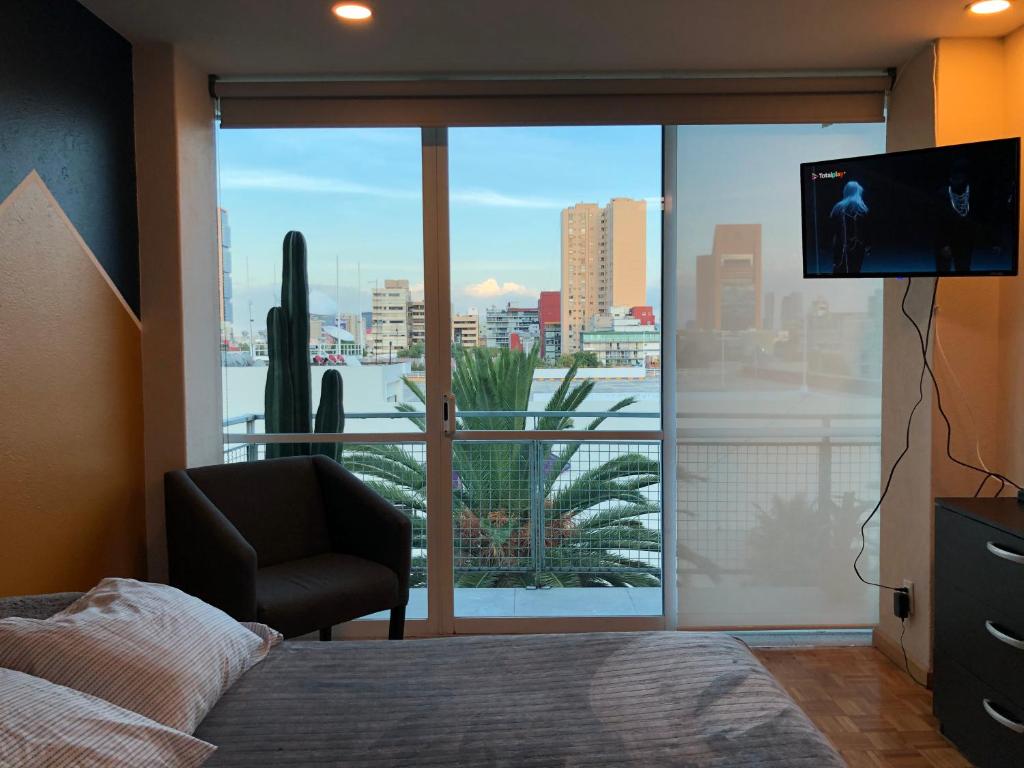 1 dormitorio con 1 cama, TV y ventana grande en Caravansaro Vazquez de Mella 347 Polanco, en Ciudad de México