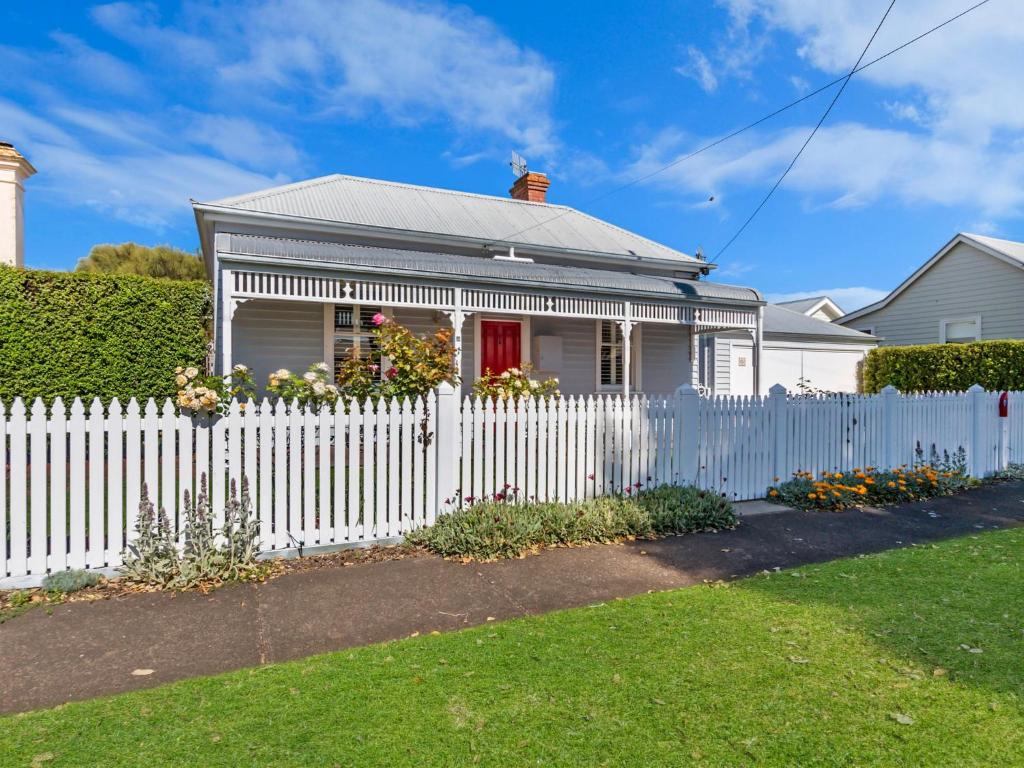 a white fence in front of a white house at Red Door at Wishart in Port Fairy