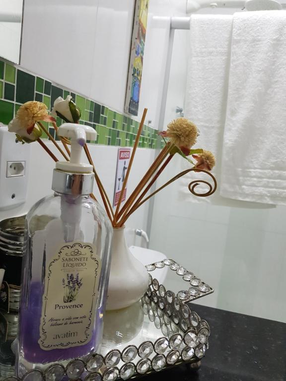 eine Flasche Parfüm und eine Vase mit Blumen auf dem Tresen in der Unterkunft Charme do Dido in Ilha de Boipeba