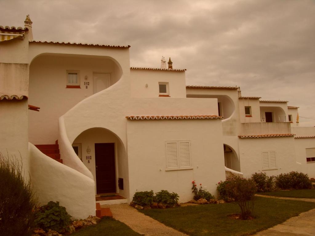 a white house with an archway in front of it at Apartamento na Vila Senhora da Rocha in Porches