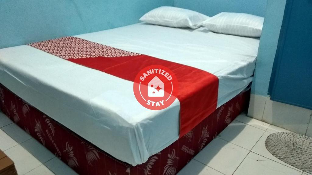 a bed with a red and white blanket on it at OYO 90001 Homestay 47 Latanete in Makassar