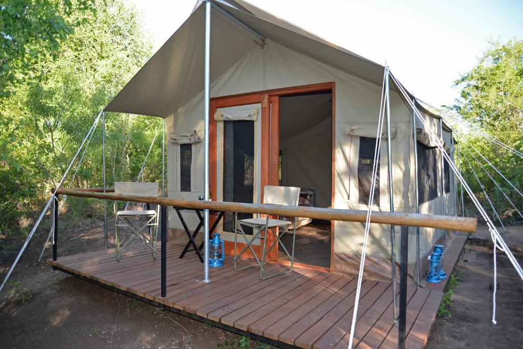 Zelt mit Tisch und Stühlen auf einer Terrasse in der Unterkunft The Wild Olive Tree Camp in Manyeleti Game Reserve