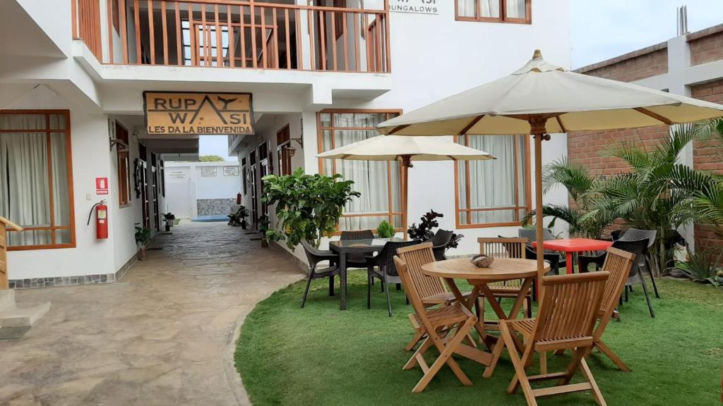 an outdoor patio with tables and chairs and umbrellas at Bungalows Rupay Wasi in Los Órganos