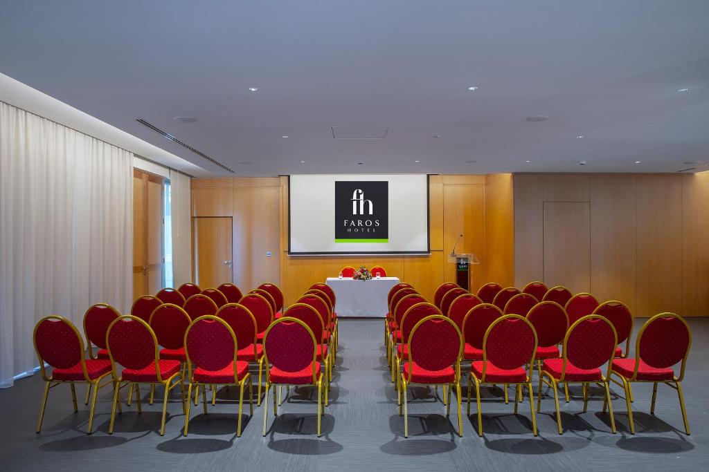 a conference room with a table and red chairs at Faros Hotel Ayia Napa in Ayia Napa