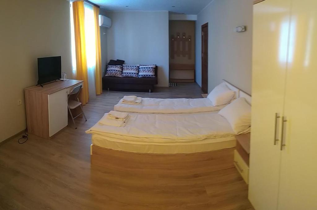 a room with two beds and a desk and a television at Стаи за гости Праматарови Огняново in Ognyanovo