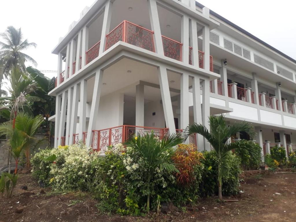 un edificio blanco con plantas y balcones rojos en KoolKost At Malalayang Manado Minimum Stay 6 Nights, en Malalayang