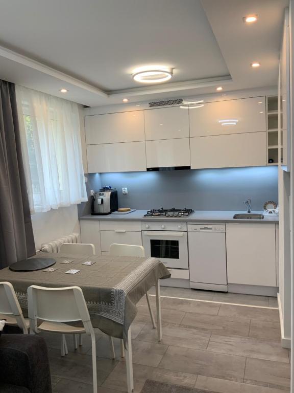 a kitchen with white cabinets and a table and chairs at White Apartment in Iwonicz-Zdrój