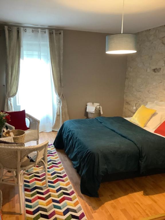1 dormitorio con cama, mesa y ventana en Maison Proche de Paris équipée, avec jardin et Wifi gratuit idéal pour les J O de Paris, en Juziers
